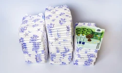 Kosten van luiers Stapel luiers, briefjes van 100, geld