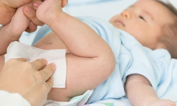 Baby ligt op een bedje en de billen worden schoongemaakt met een babydoekje Baby ligt op een bedje en de billen worden schoongemaakt met een babydoekje