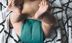 Baby ligt met een een groene wasbare luier op een dekentje Baby ligt met een een groene wasbare luier op een dekentje
